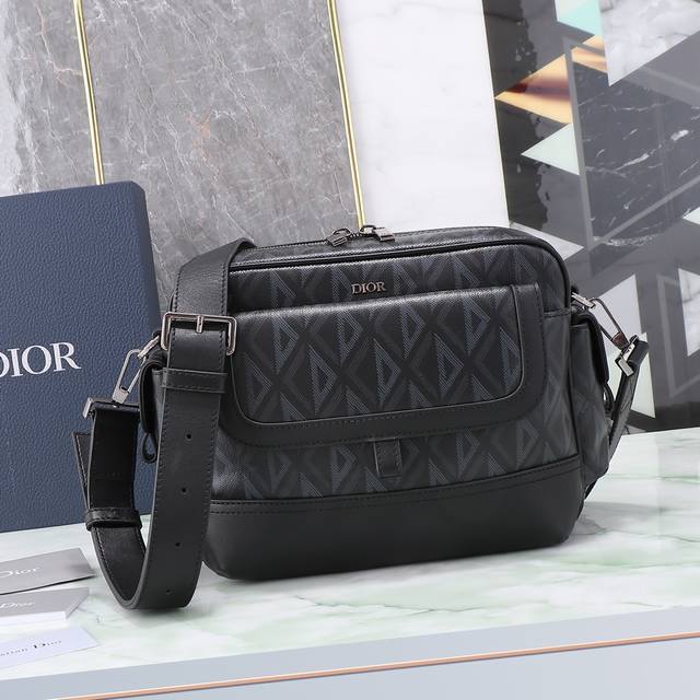 这款 Dior Hit The Road 信使包是本季新品 将现代风格与 Dior 的高订精神融为一体 采用迪奥黑cd Diamond 图案帆布和光滑牛皮革精心