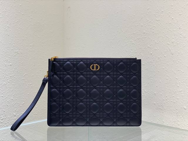 Dior Caro 日常手拿包是一款优雅实用的单品 采用黑色 柔软牛皮革精心制作 饰以标志性的藤格纹缉面线 正面点缀以 Cd 标志 大号款式 可收纳各种日常用品