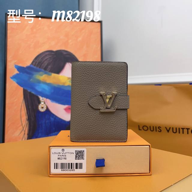 Lv Vertical 短款钱夹 M82198杏色 此次取材粒面 Taurillon 皮革 呈现内外色彩反差 Lv 字母滑扣援引 Capucines 手袋的开合