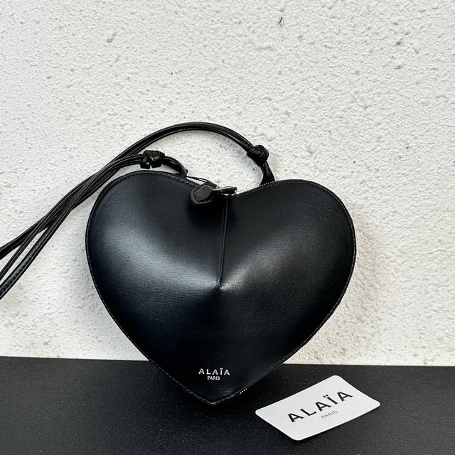 Alaia Coeur Bag 爱心手袋系列，立体爱心设计辨识度超高，拉链袋配有可调式的肩带，非常适合携带必需品，造型简洁，包包印有精致的 Logo 银色浮雕标