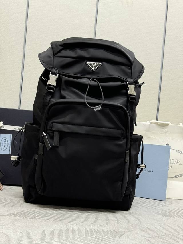 新款登山包2Vz090 这款背包颇具科技外观搭配实用性内部空间。采用re-Nylon再生尼龙打造，Saffiano皮革呈现出交叉排线和涂蜡饰面。细节格调鲜明。象